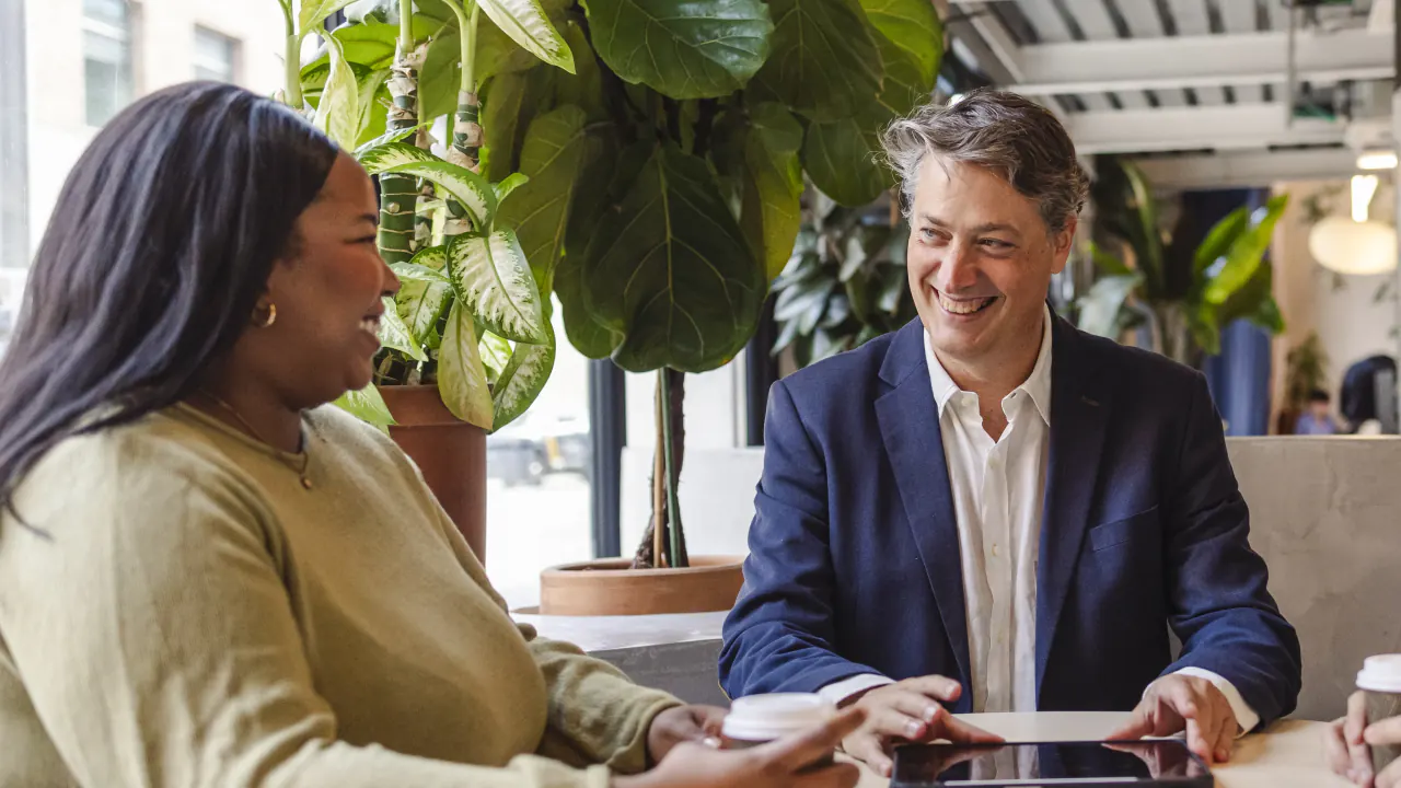 Two professionals in conversation in a bright office, illustrating signs it is time to outsource your sales calls