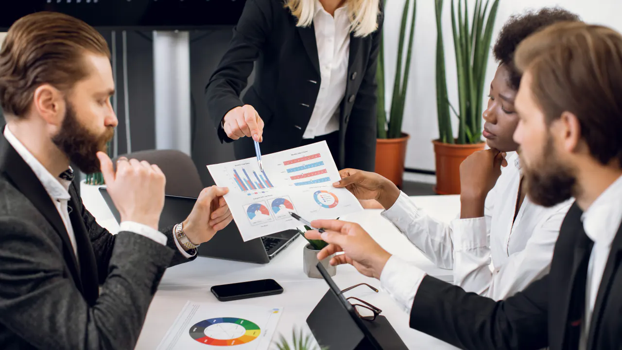 Marketing team reviewing printed charts around a table, illustrating alternatives to Abstrakt Marketing Group