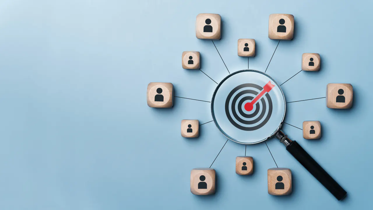 Magnifying glass over a target surrounded by customer icons, illustrating account based marketing