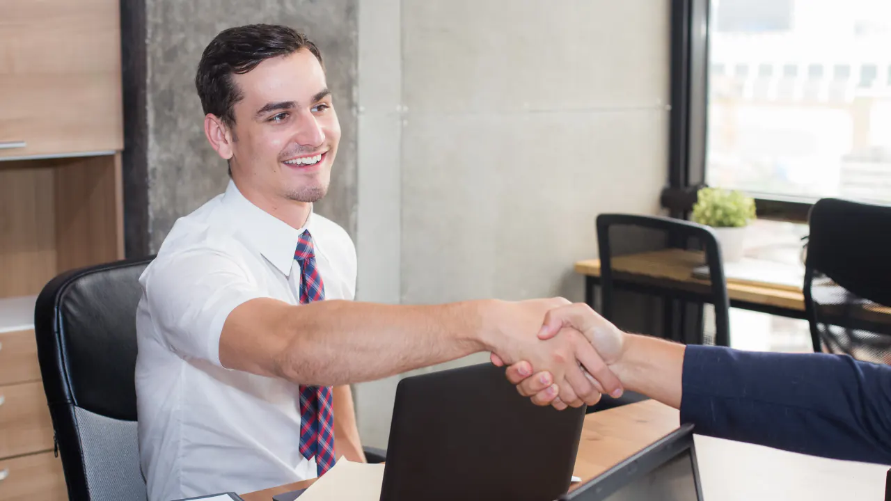 Account manager shaking hands with a client in an office, illustrating the account manager role