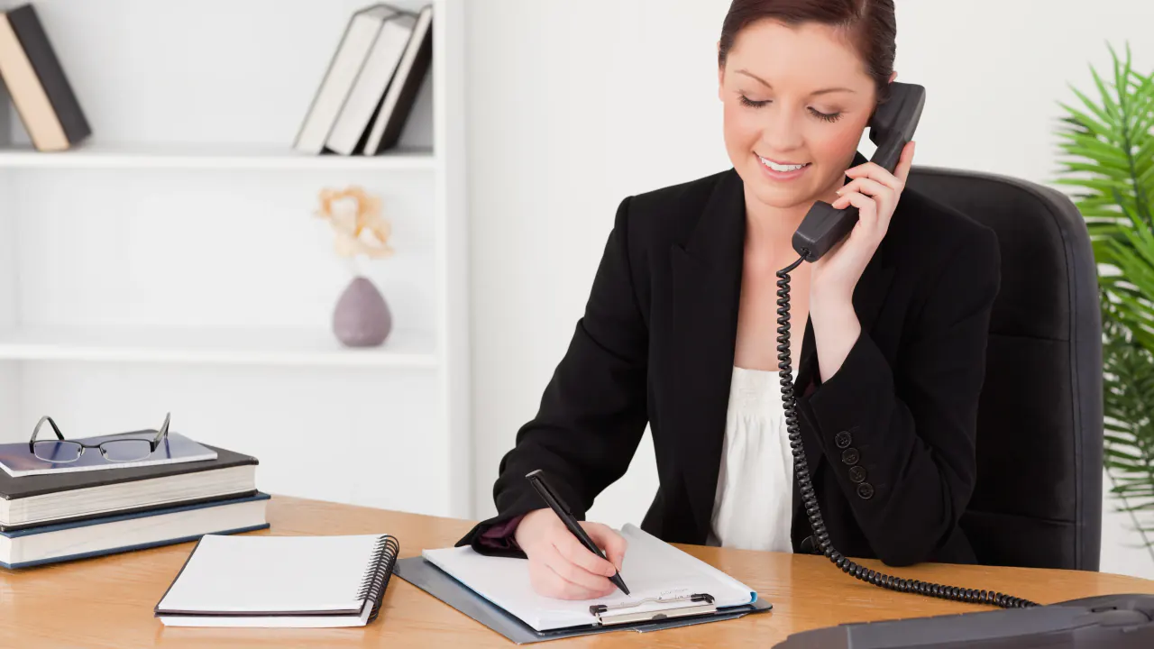 Businesswoman on a desk phone taking notes, illustrating cold call appointment setting techniques