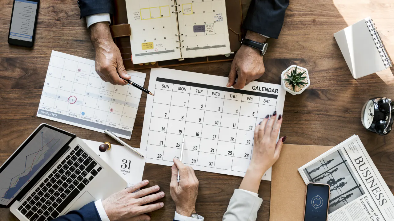Calendar, planner and laptop on a desk with hands scheduling, illustrating B2B appointment setting
