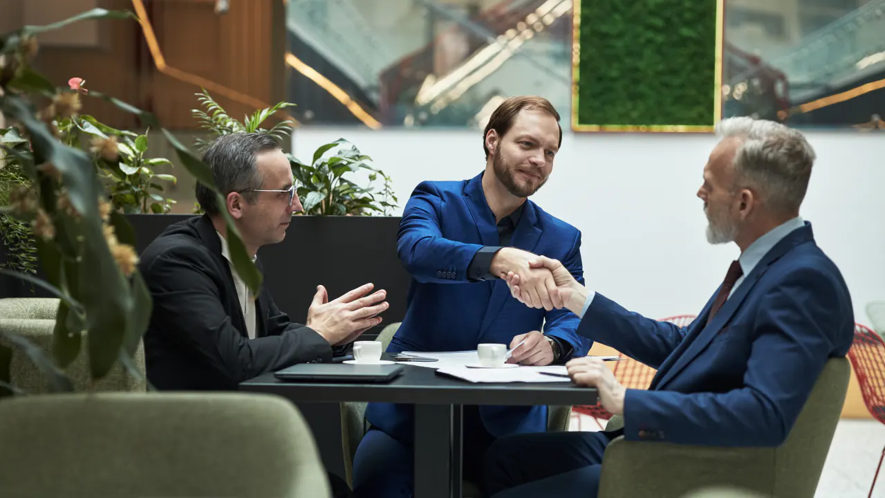 Businessmen shaking hands at a meeting table, illustrating B2B prospecting for high-value leads