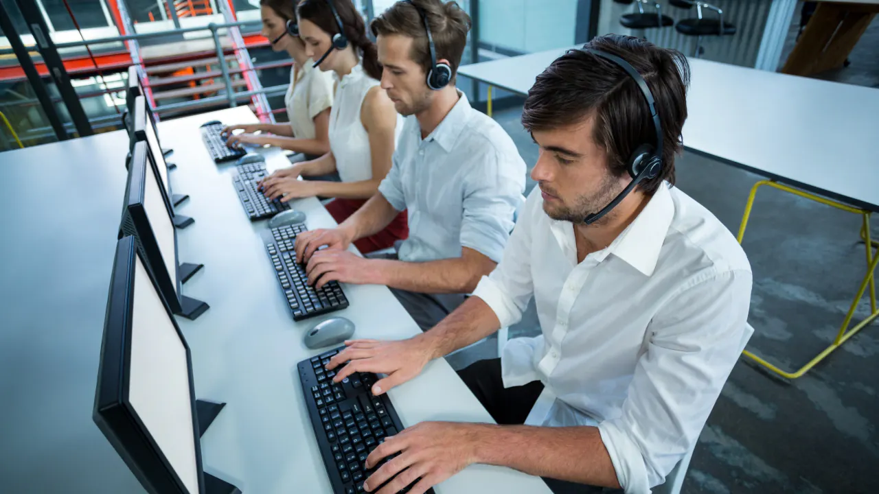 Sales reps wearing headsets at computers, illustrating B2B sales prospecting strategies