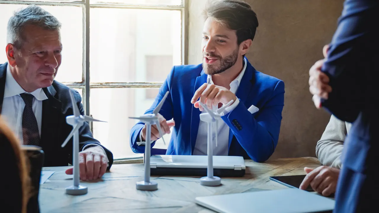 Businessmen discussing wind turbine models at a table, illustrating what still works in B2B telemarketing