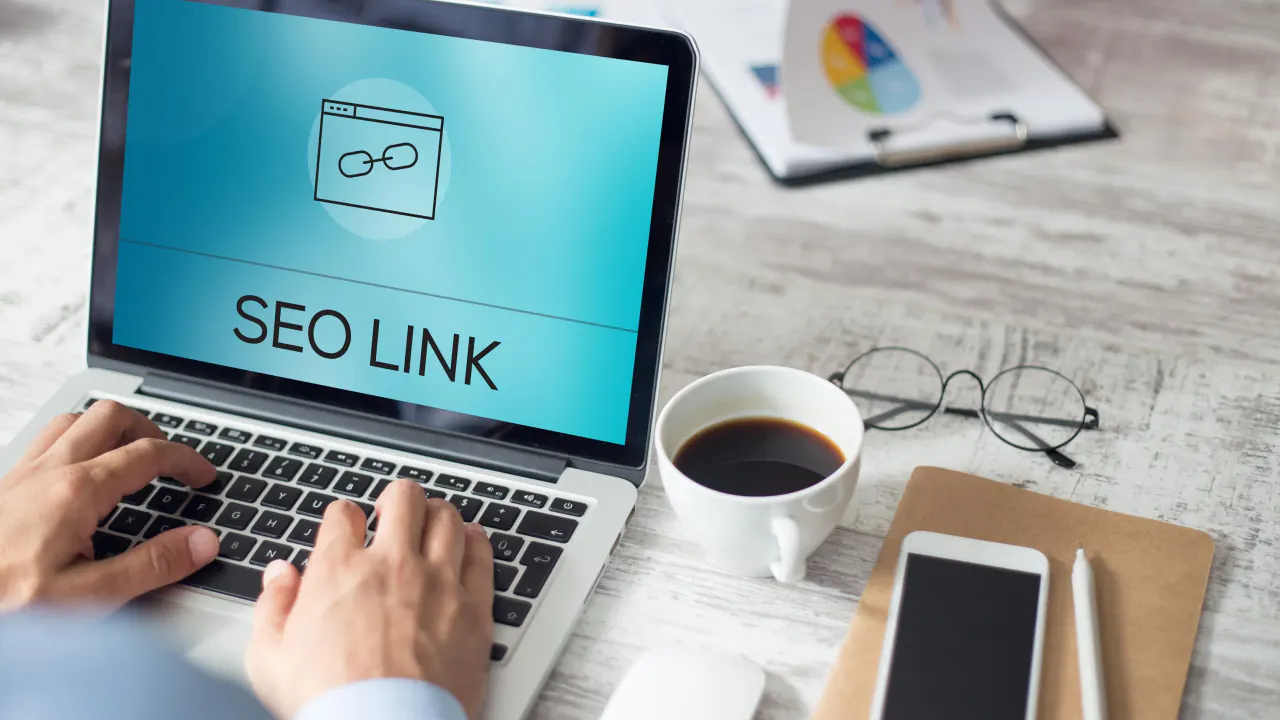 Hands typing on a laptop displaying an SEO link icon, illustrating backlinks