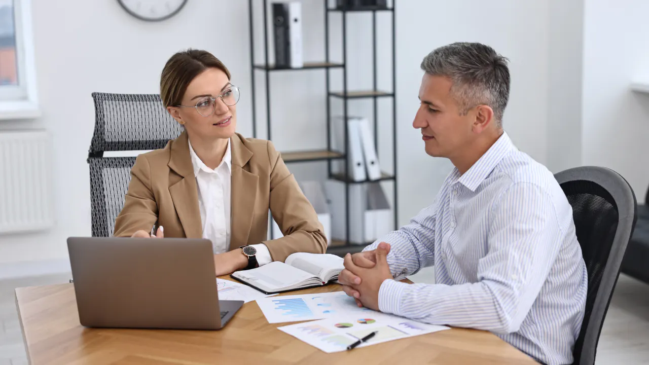 Financial advisor meeting with a client at a desk, illustrating lead generation for financial advisors