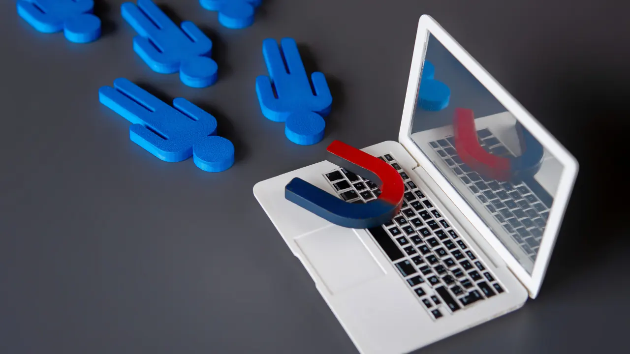 Magnet pulling blue figures toward a laptop, illustrating the best tools for lead generation