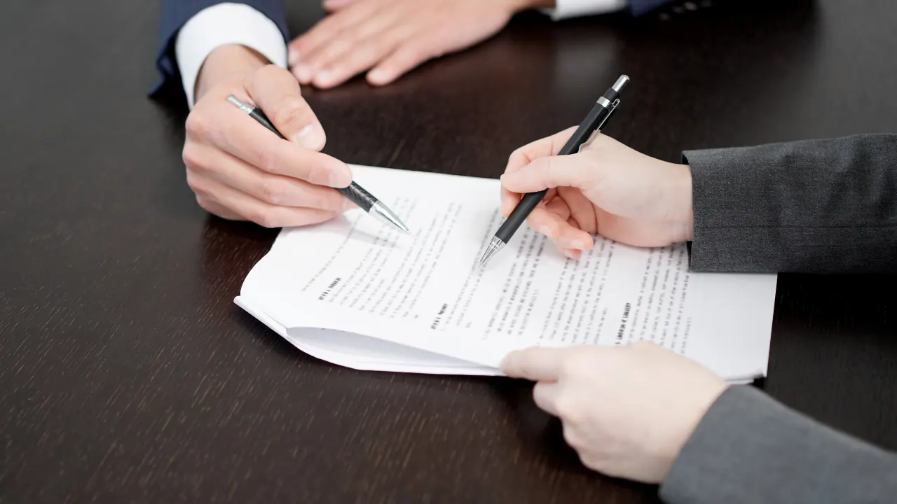 Two people signing a contract at a table, illustrating the bottom of the funnel