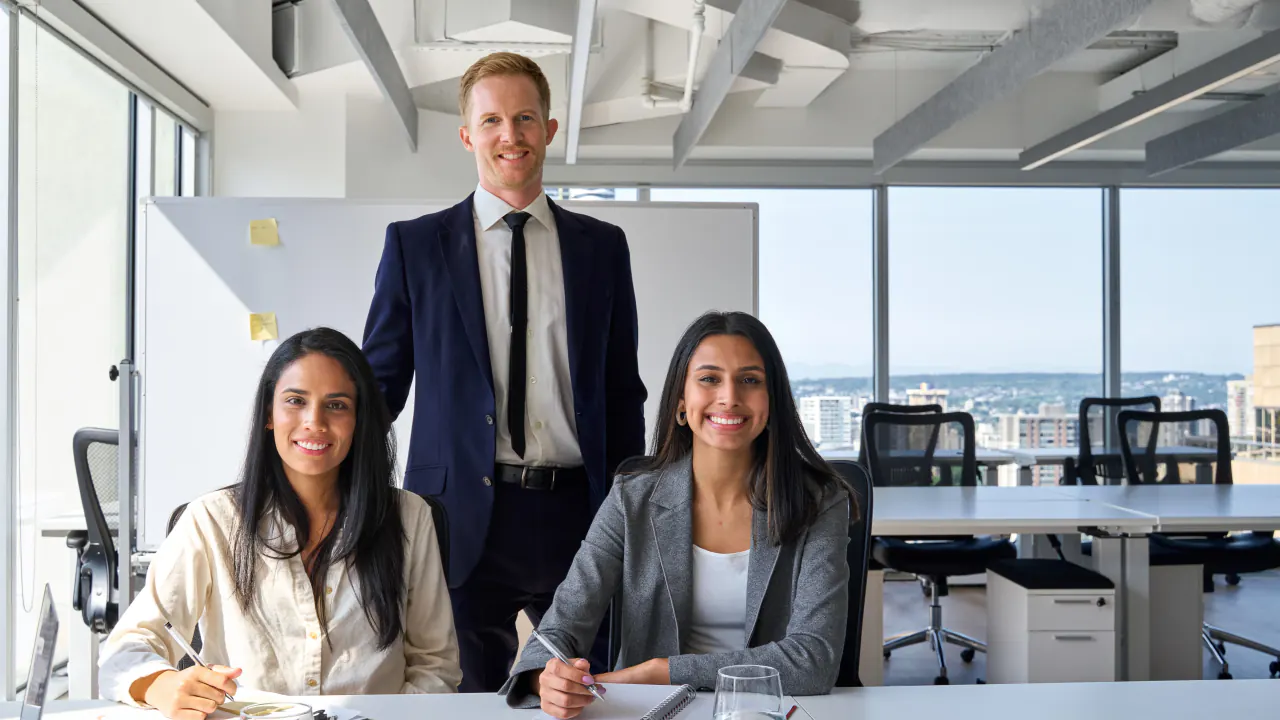 Three professional services colleagues smiling in a bright office, illustrating brand positioning strategy