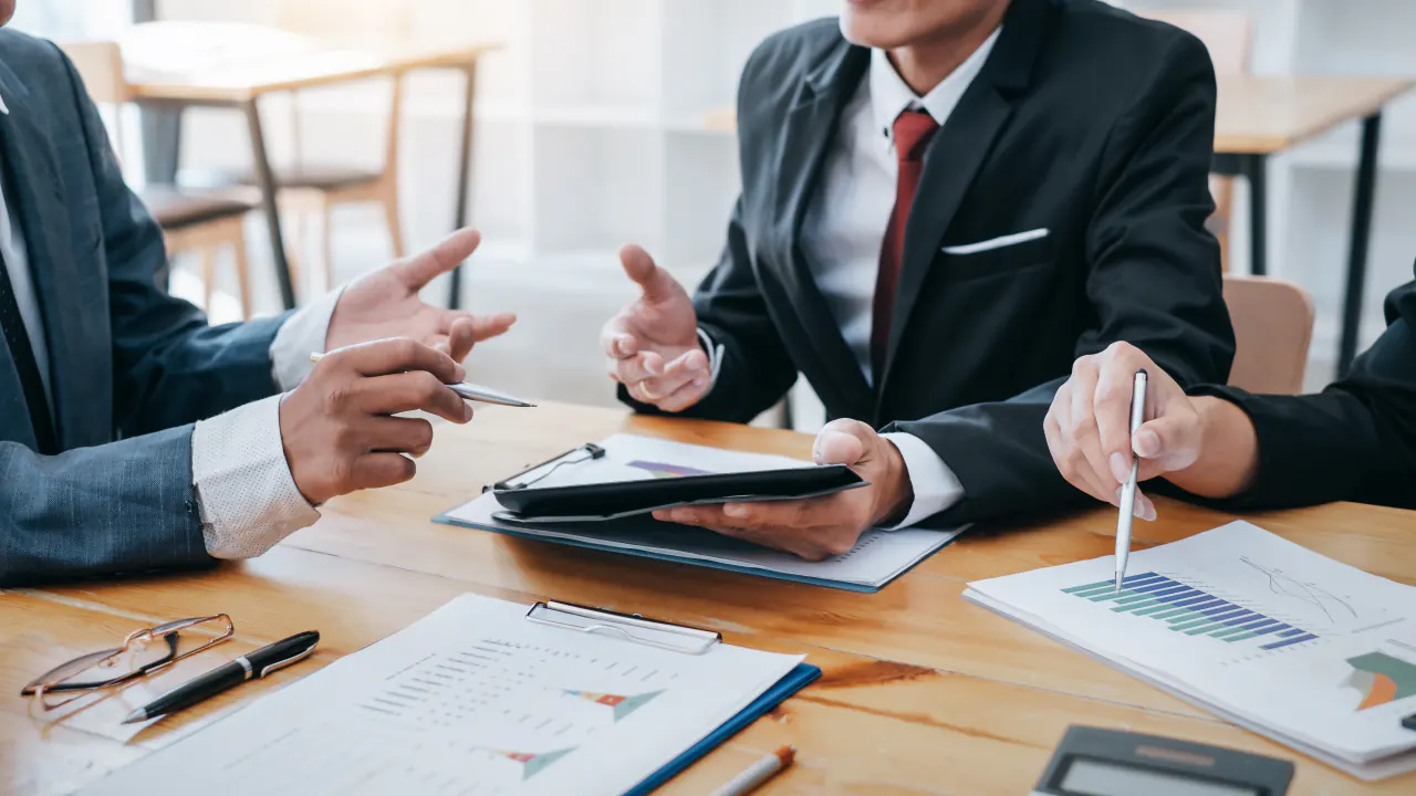 Financial professionals reviewing charts at a meeting table, illustrating B2B lead generation agencies for financial services