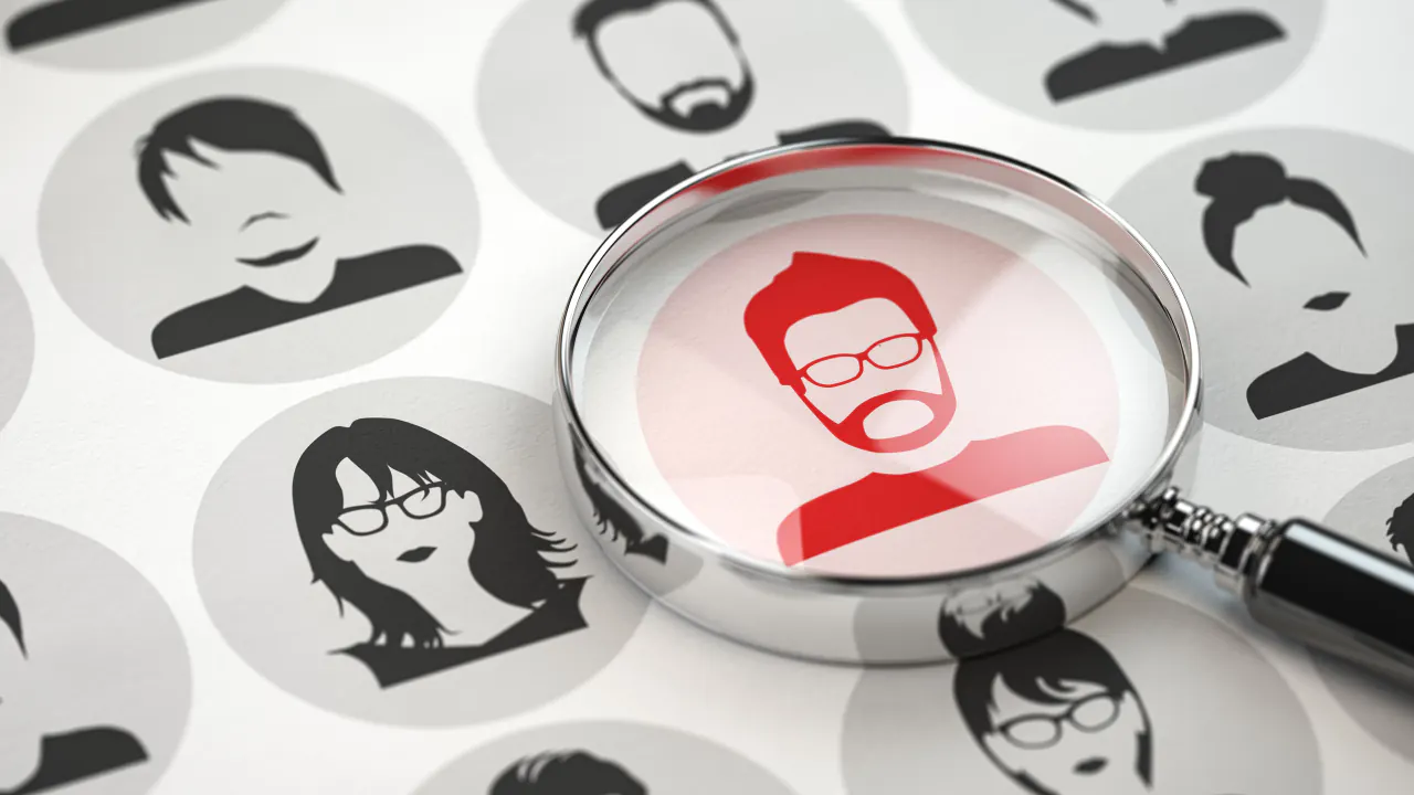 Magnifying glass over a profile icon among customer avatars, illustrating a buyer persona