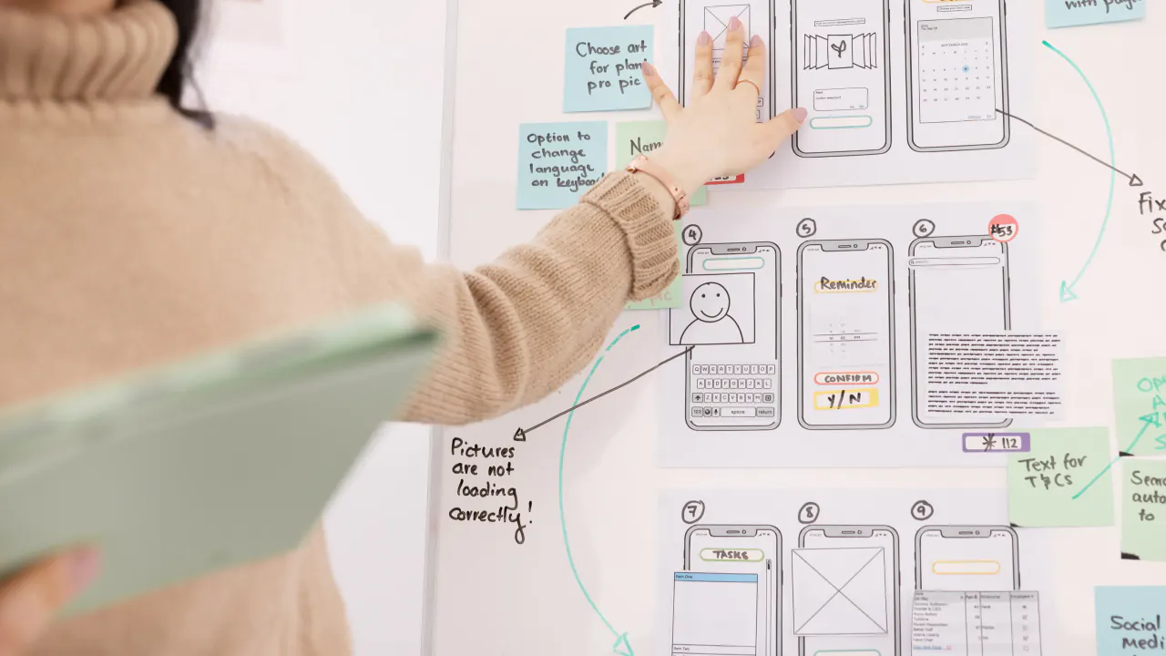 Woman pointing at app wireframes on a whiteboard, illustrating the buyer's journey