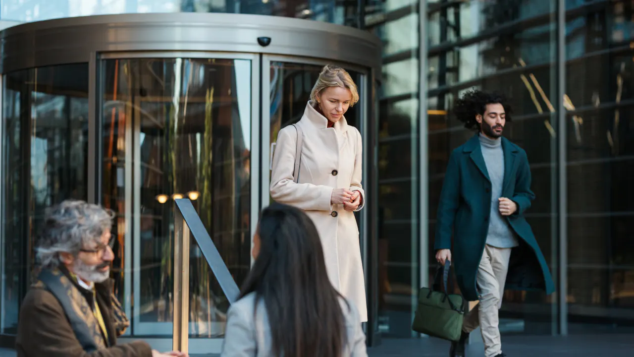 Professionals walking through office revolving doors, illustrating customer churn rate
