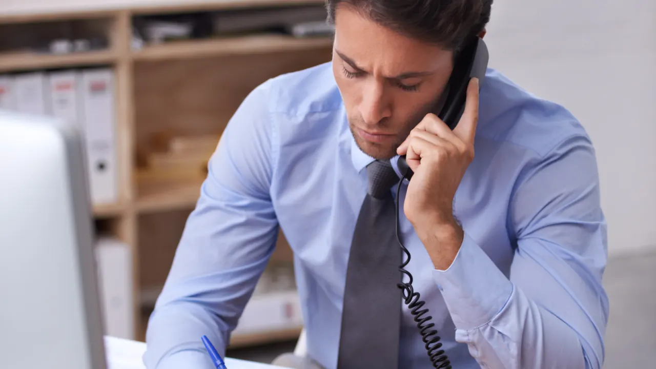 Businessman on a desk phone making a call, illustrating B2B cold calling