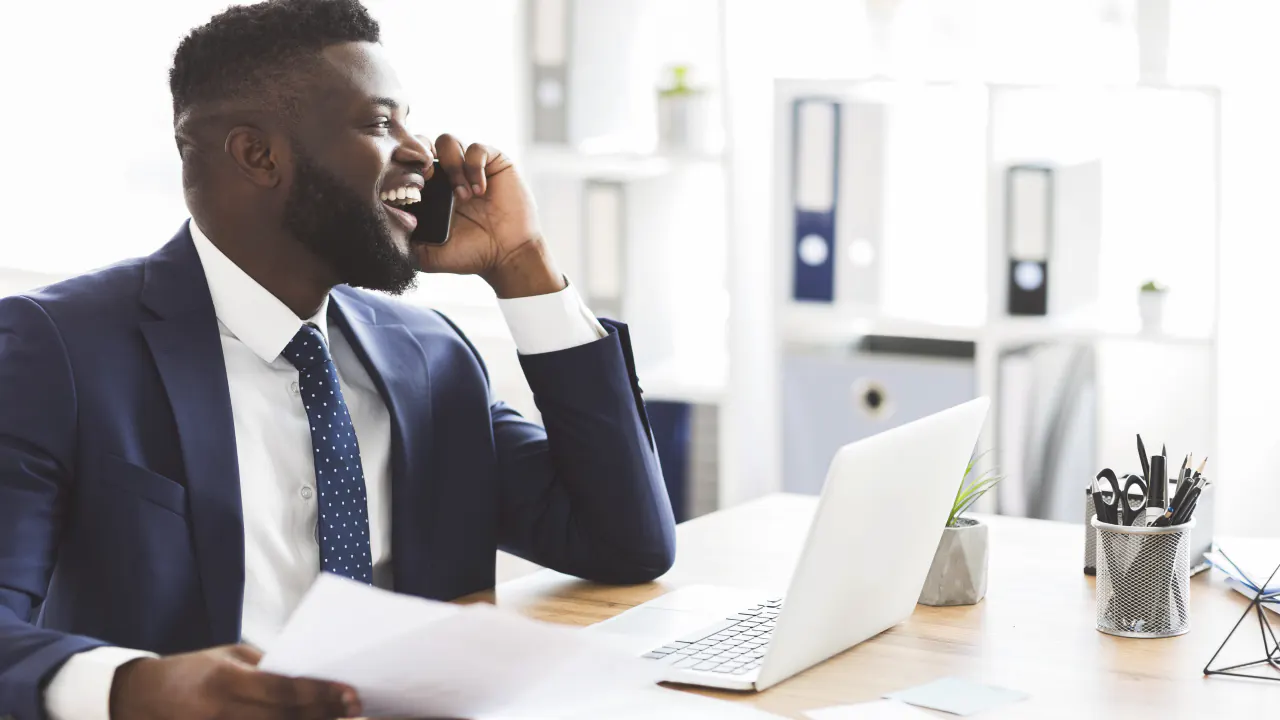 Businessman on a phone call beside a laptop, illustrating US appointment setters for commercial insurance brokers