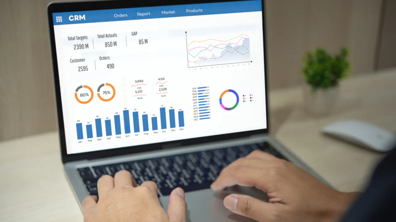 Hands on a laptop displaying CRM analytics charts, illustrating customer relationship management analytics