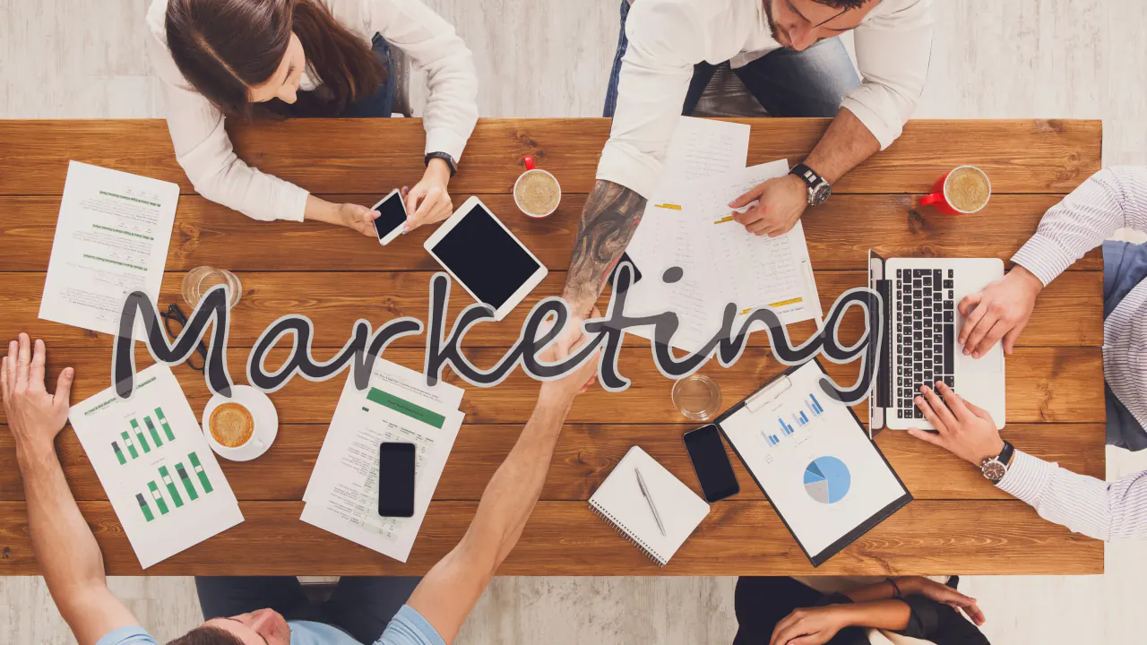 Team around a table with marketing reports and devices, illustrating how to find customer acquisition services