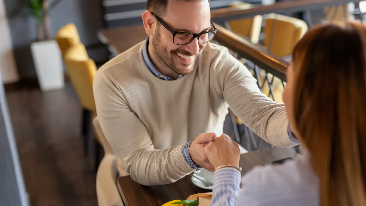 Smiling man fist-bumping a client in a cafe, illustrating customer lifetime value