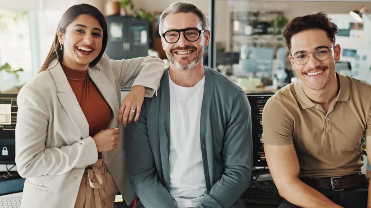 Three smiling colleagues posing together in an office, illustrating customer marketing