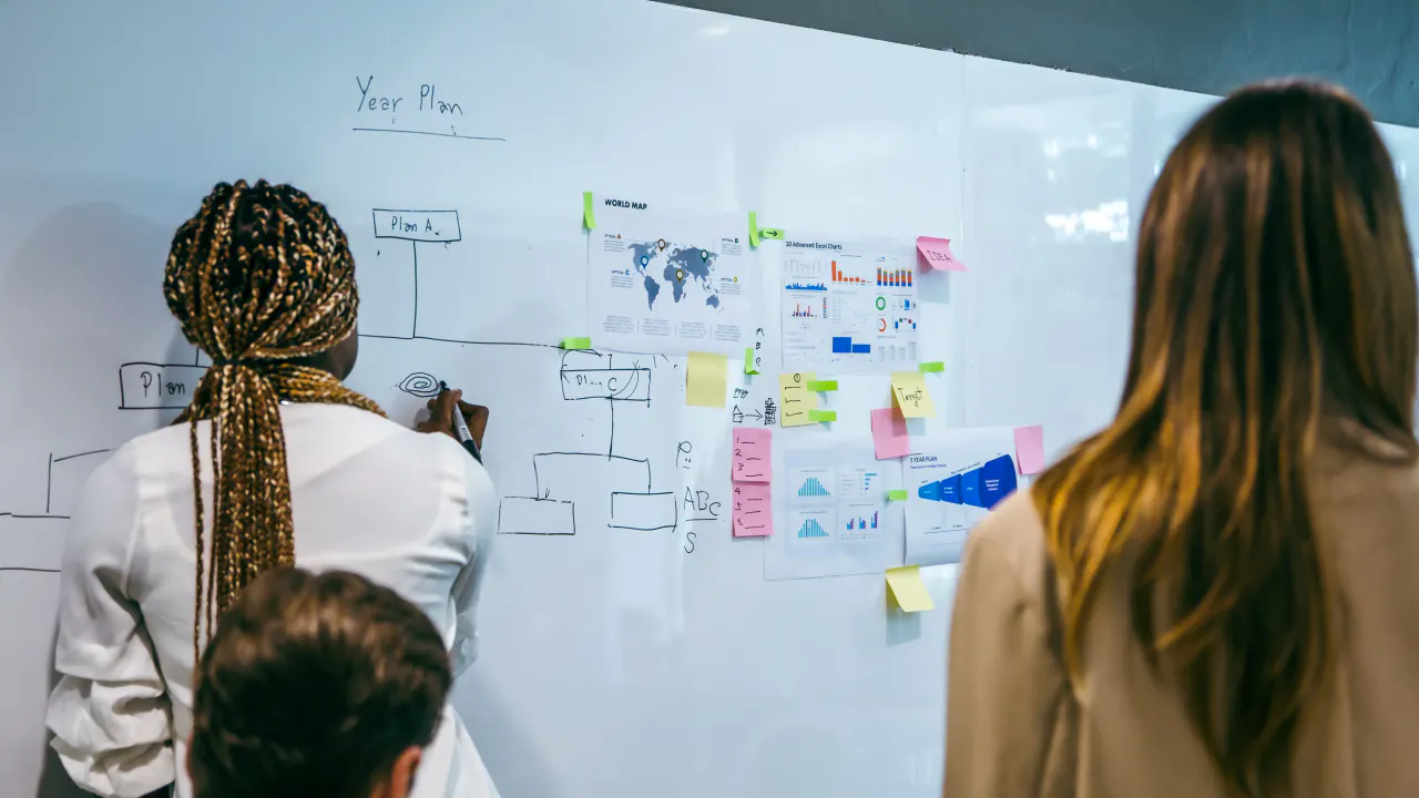 Colleagues mapping a plan on a whiteboard, illustrating demand generation vs. lead generation