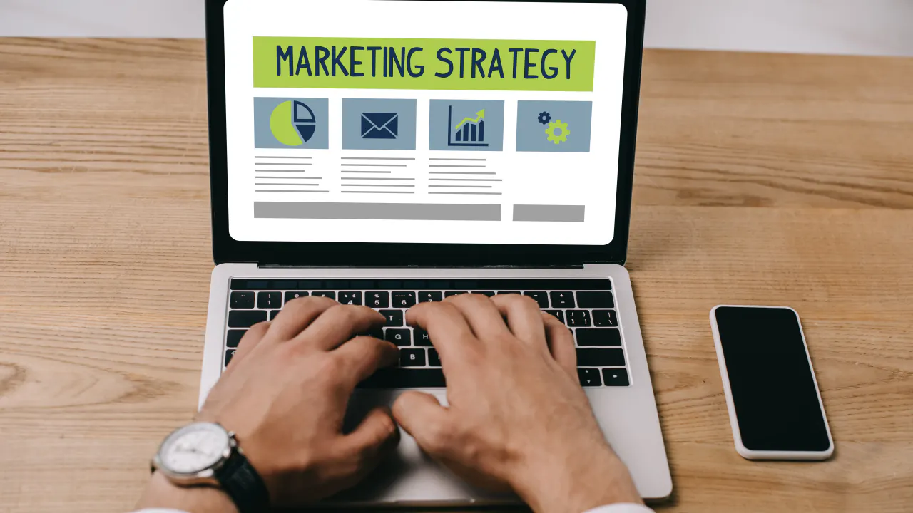 Hands typing on a laptop showing a marketing strategy dashboard, representing B2B demand generation
