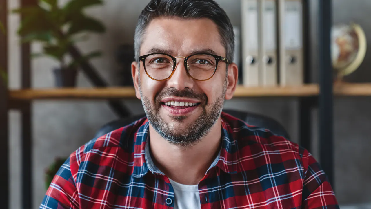 Smiling professional in a plaid shirt ready for a B2B discovery call with a prospect