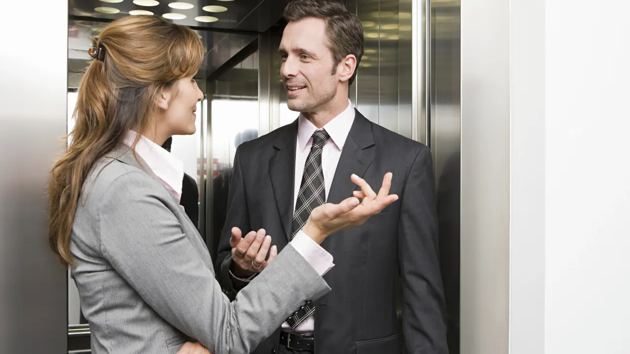 Two business professionals talking in an elevator, illustrating elevator pitch examples