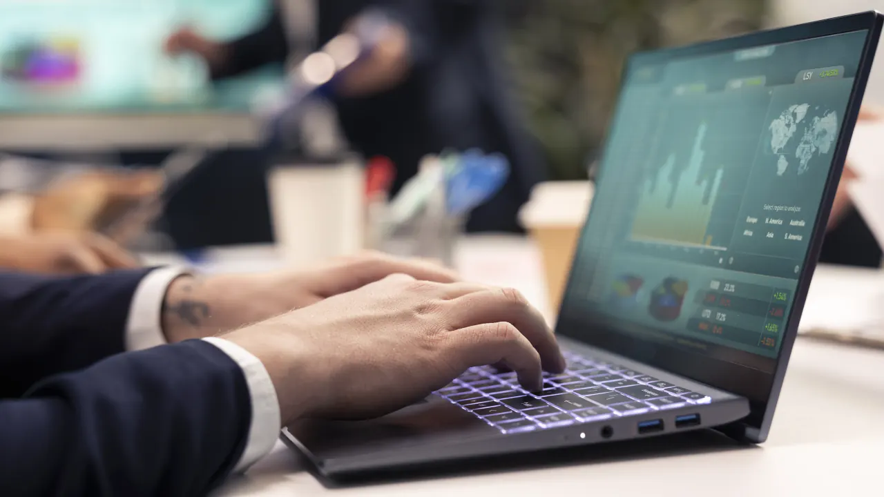 Hands typing on a laptop with analytics on screen, representing choosing enterprise sales software
