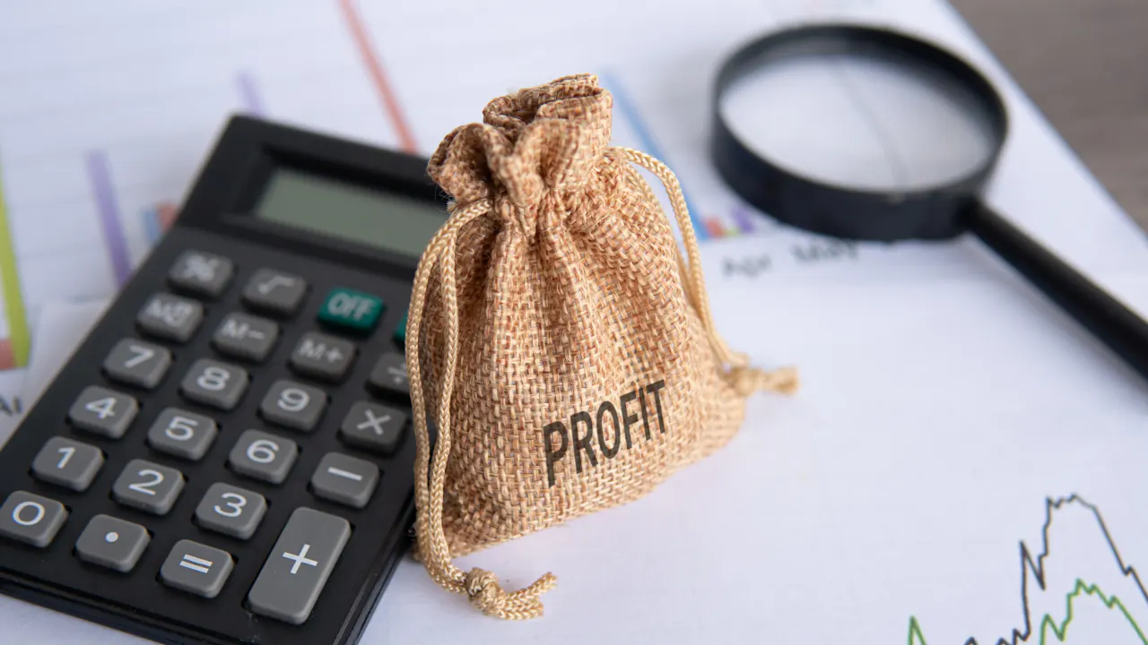 Calculator and profit money bag on financial charts, illustrating how to calculate profit margin