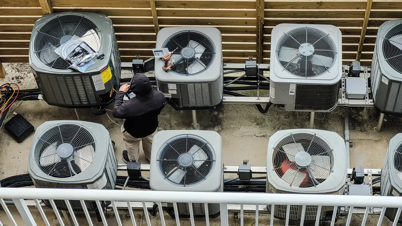 Aerial view of rooftop HVAC condensers with a technician, illustrating 18 years of HVAC appointment setting