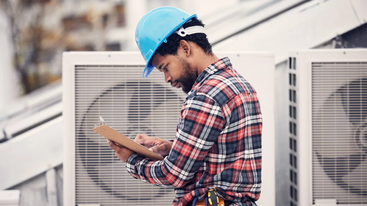 HVAC technician in a hard hat checking rooftop air conditioning units, illustrating how to generate HVAC leads