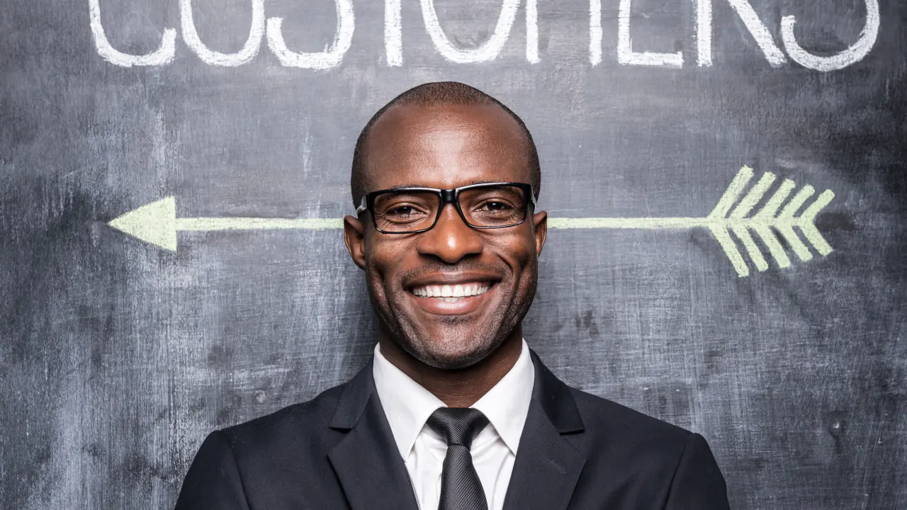 Smiling businessman in front of a customers chalkboard arrow, illustrating what ICP means in sales