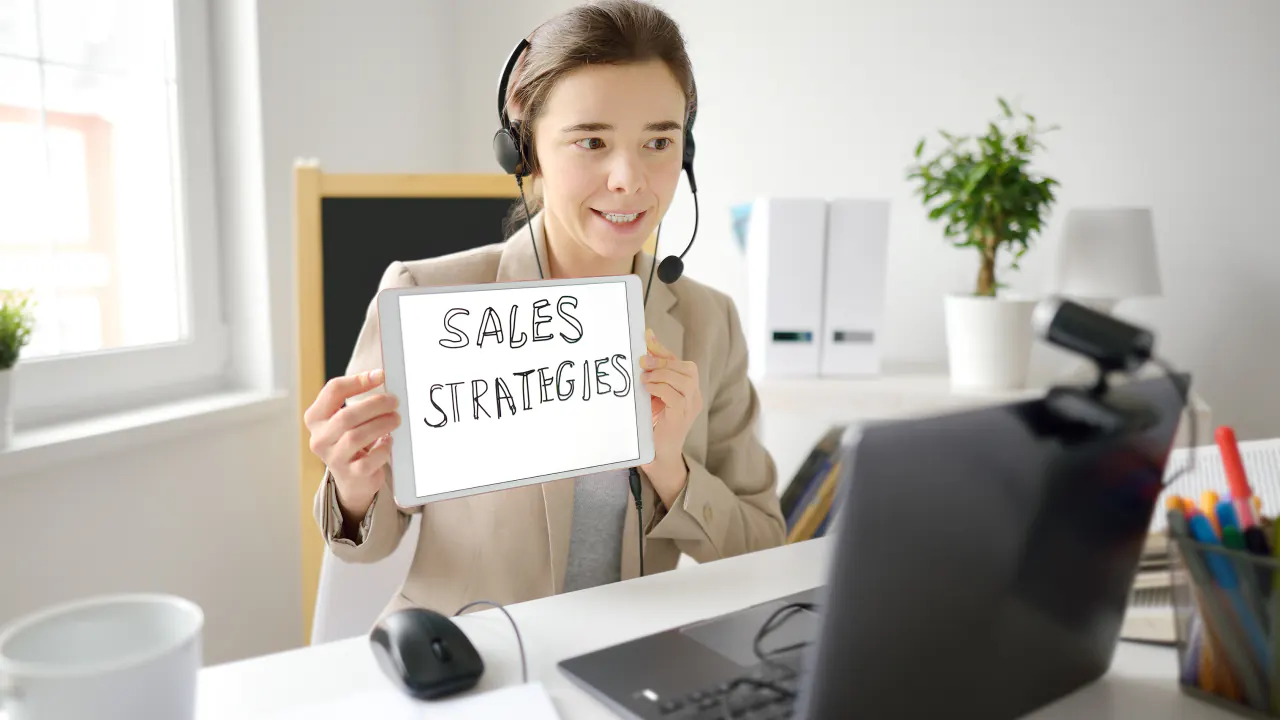 SDR agent in a headset holding a Sales Strategies sign, illustrating how to compare outsourced B2B SDR agencies