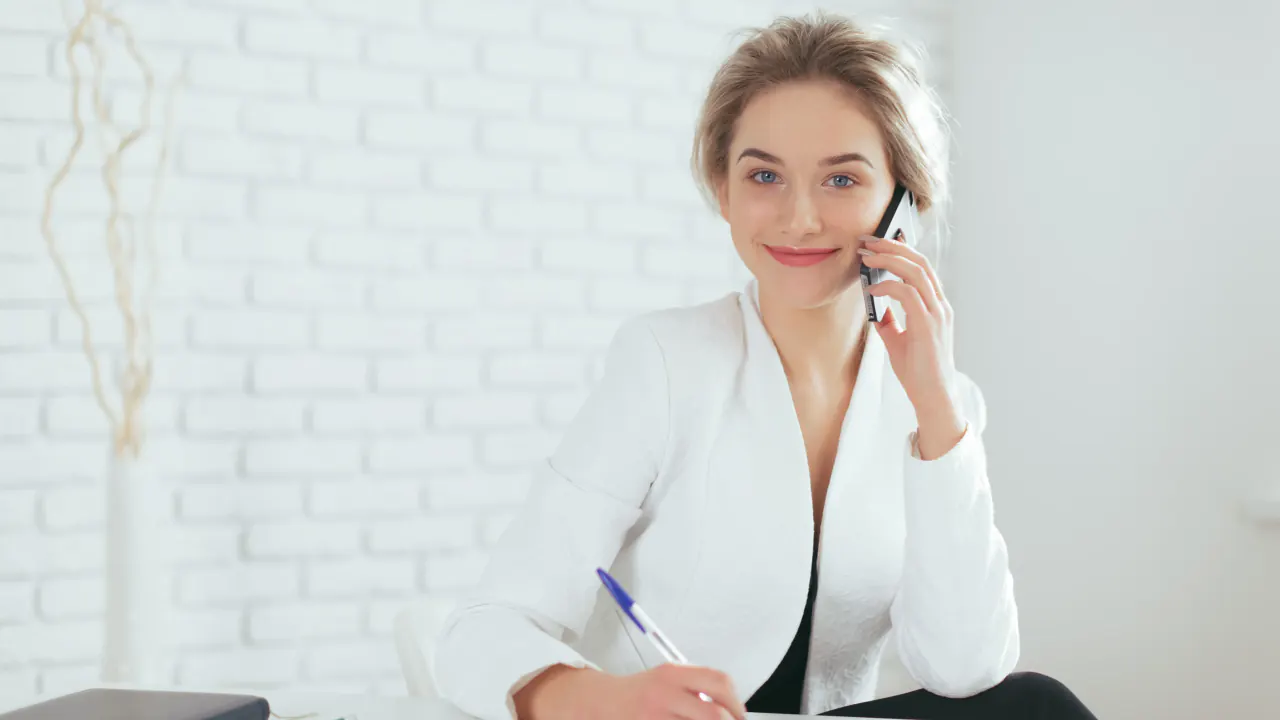 Insurance professional smiling on a phone call while taking notes, illustrating strategies for quality insurance leads