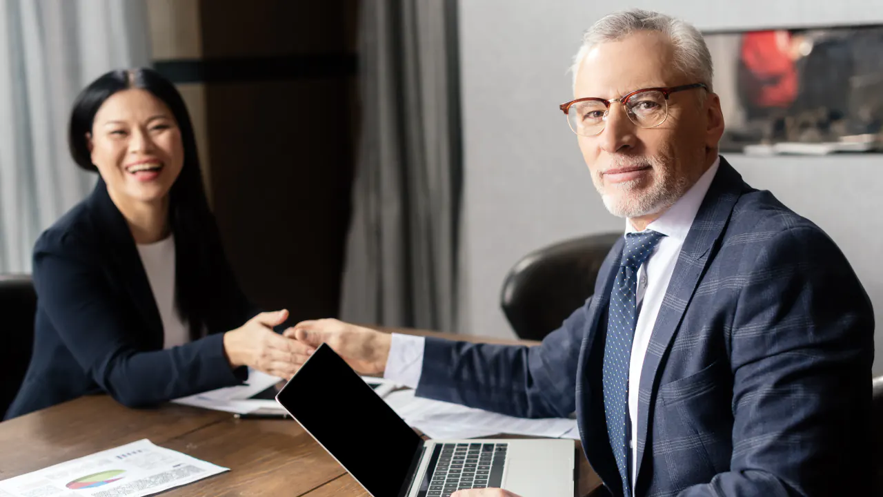 Business professionals shaking hands across a desk, illustrating how to score high-quality IT sales leads