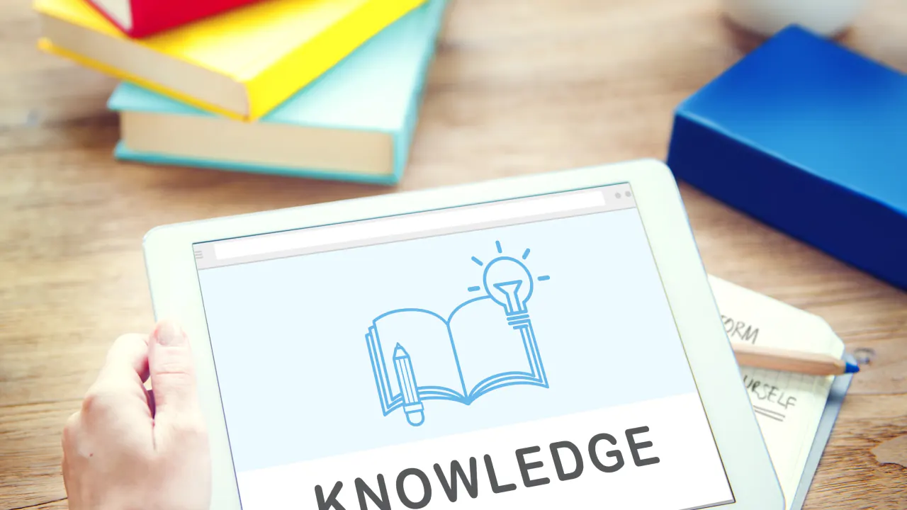 Hand holding a tablet showing a knowledge base icon, illustrating what a knowledge base is