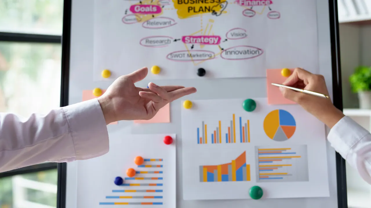 Hands pointing at a business plan whiteboard with charts, illustrating proactive lead generation tips