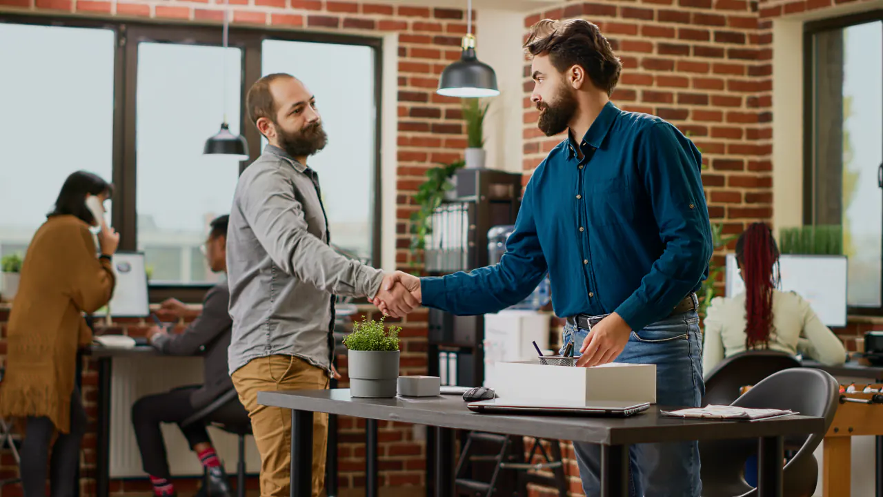 Two businessmen shaking hands in a loft office, illustrating the best B2B lead generation companies in the US