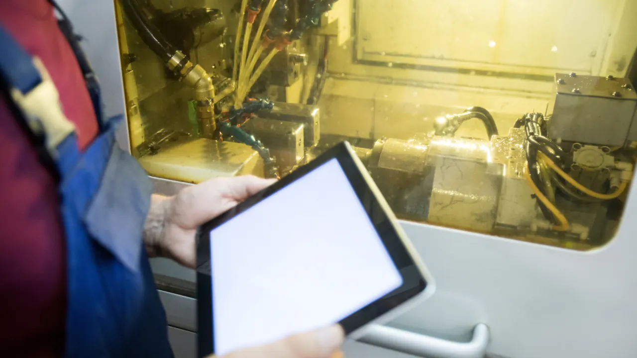 Technician holding a tablet beside industrial machinery, illustrating B2B lead generation for manufacturers