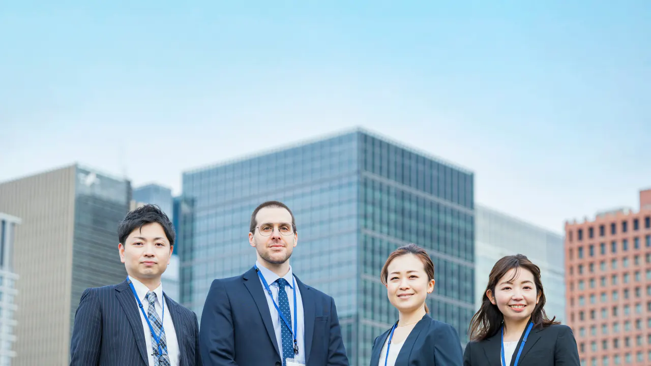 Team of four business professionals outside city office towers, representing mid-market vs enterprise sales tactics