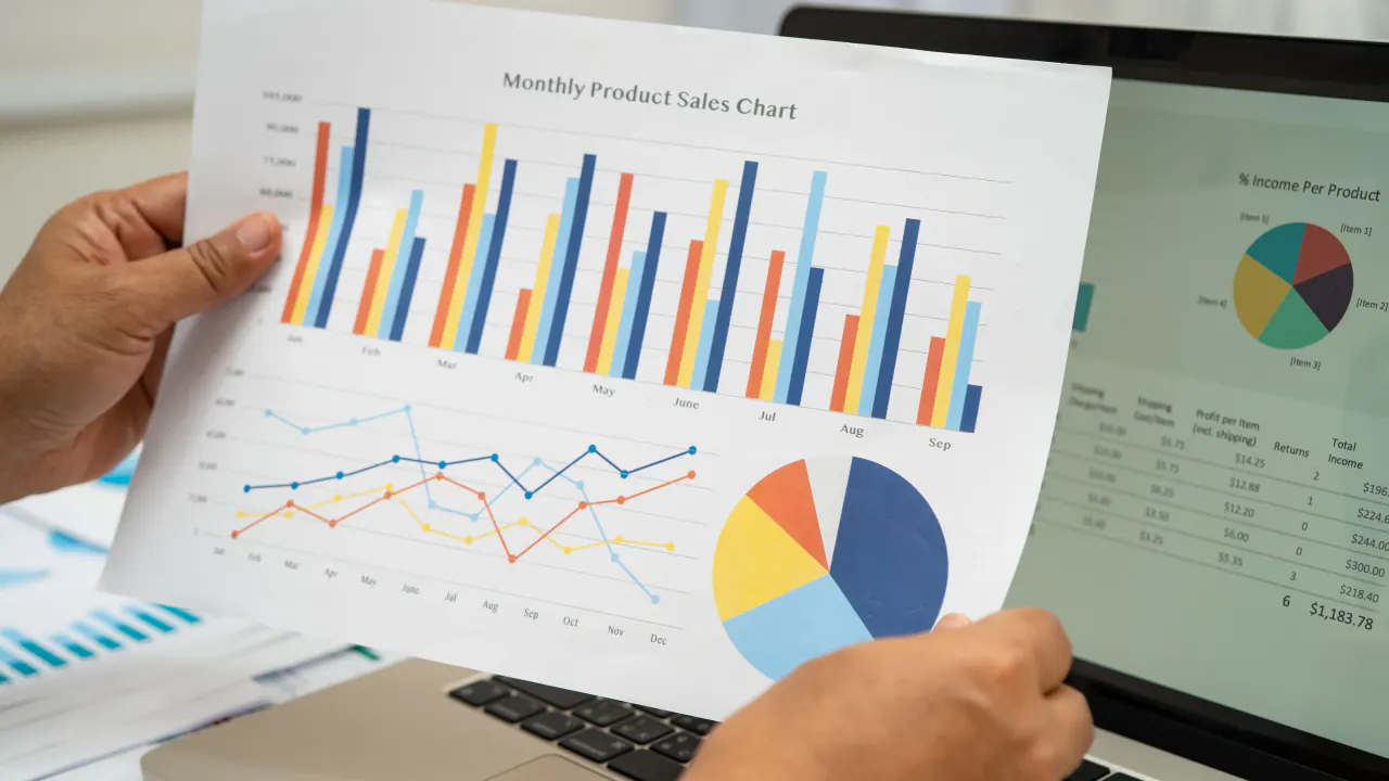 Hands holding a monthly product sales chart, illustrating multi-touch attribution