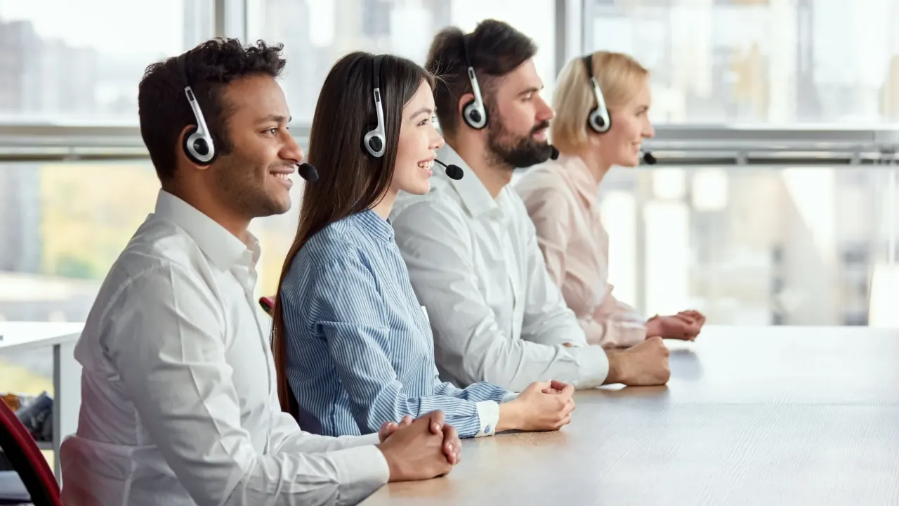 Call center team with headsets seated at a table, illustrating how to run an outbound calling campaign