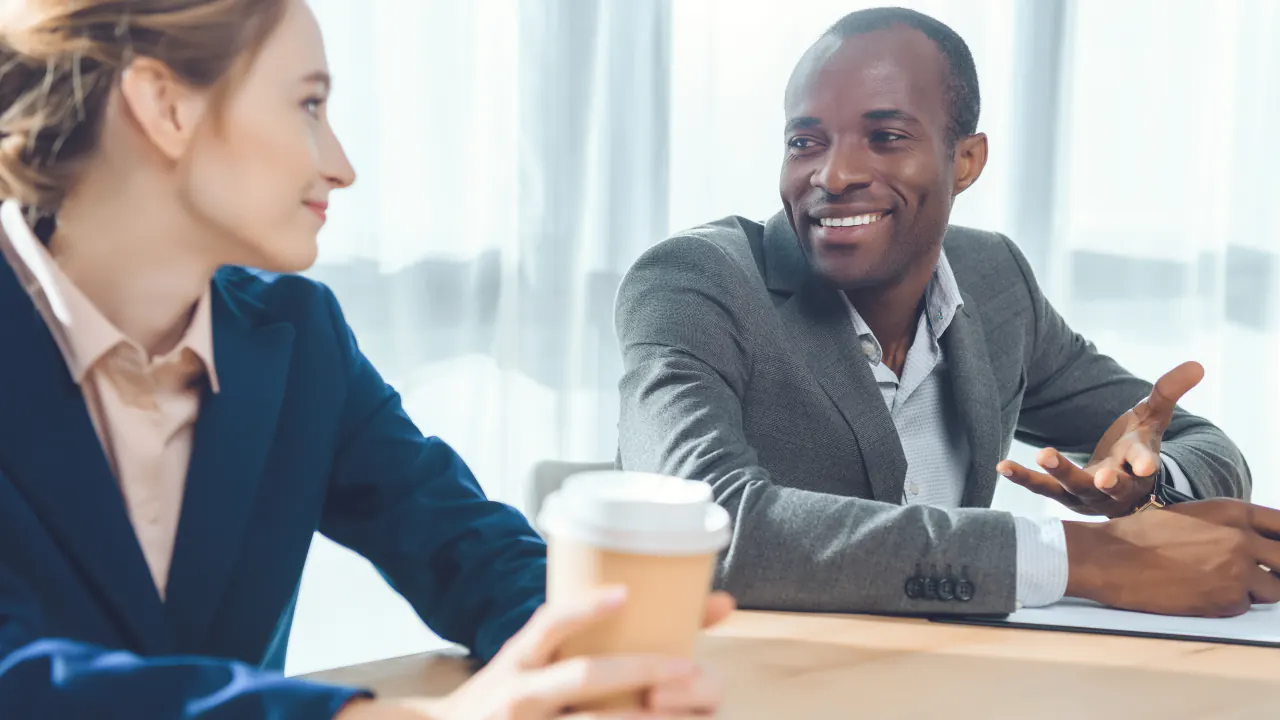 Two colleagues discussing ideas over coffee, illustrating how to write strong positioning statements