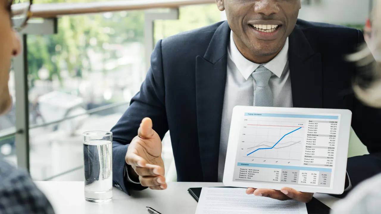 Smiling executive showing a growth chart on a tablet to a client, illustrating a qualified prospect