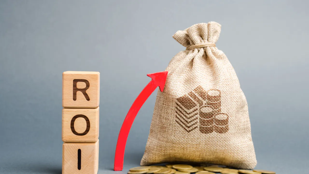 Wooden ROI blocks beside a money bag and rising arrow, illustrating return on investment (ROI)