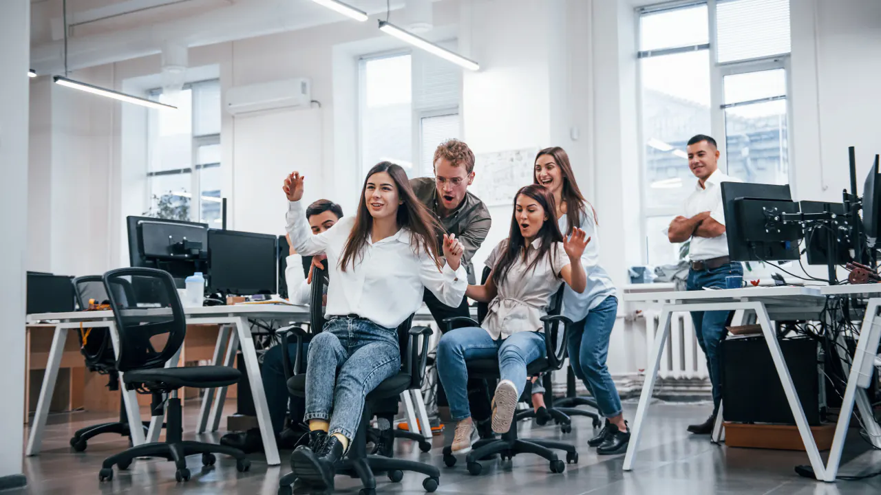 Office team cheering at their workstations, illustrating sales outsourcing services that help a business scale
