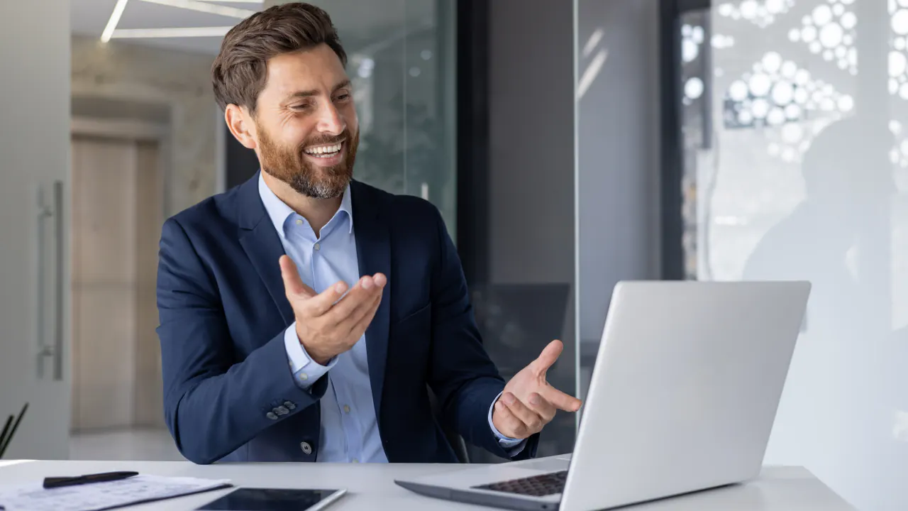 Smiling salesman gesturing beside a laptop, illustrating sales prospecting tools