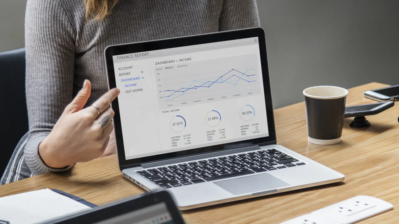 Hand pointing at a sales report chart on a laptop, illustrating ways to improve software sales