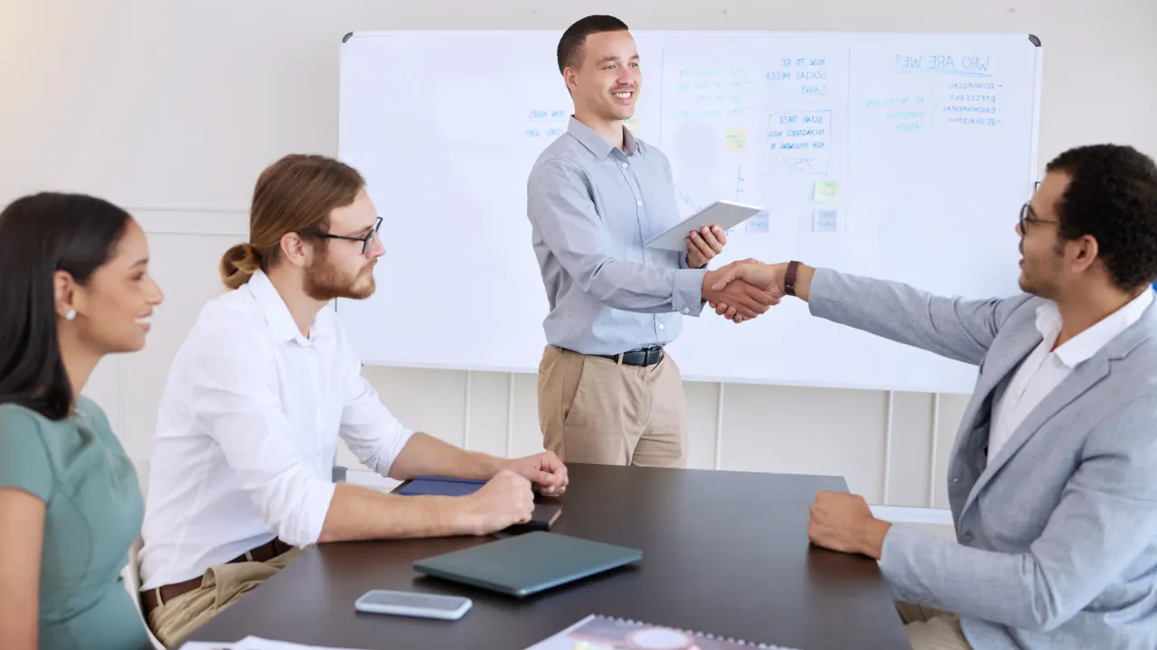 Business team handshake at a conference table, illustrating a sales qualified lead (SQL)